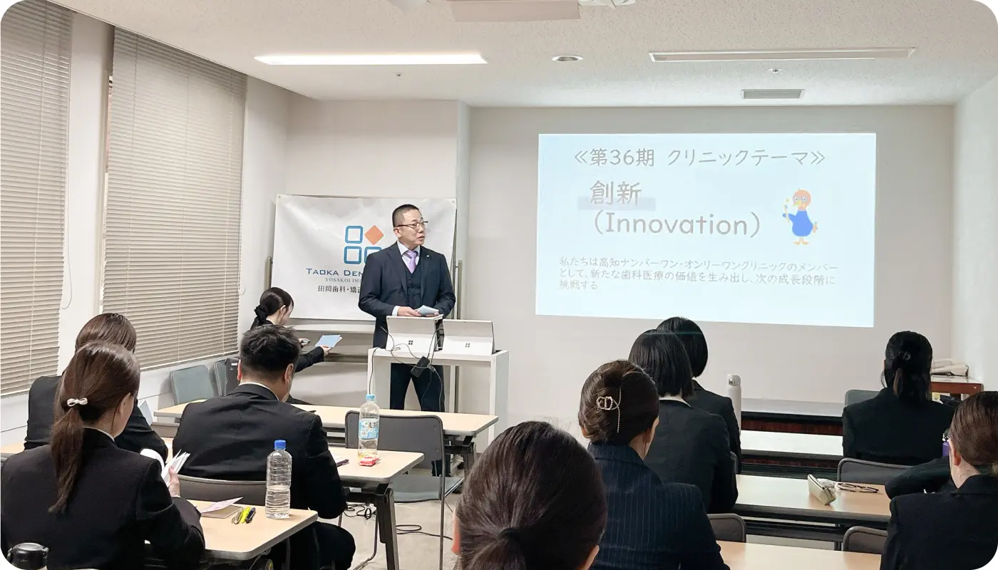 クリニックの経営方針発表会で「創新（Innovation）」をテーマにプレゼンテーションを行う院長とスタッフ。