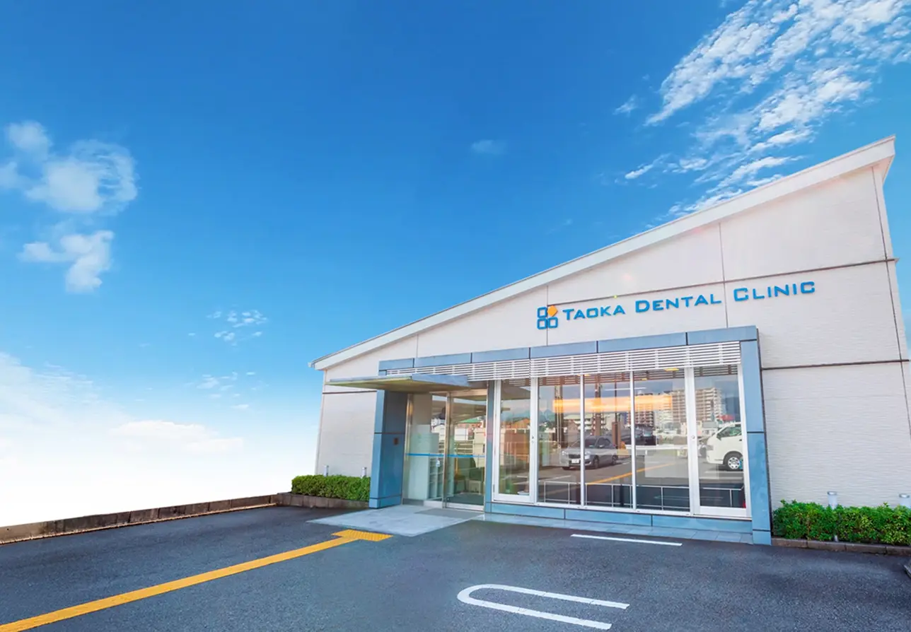 大きな窓とモダンな外装が特徴的な田岡歯科矯正歯科の建物外観と広々とした駐車場