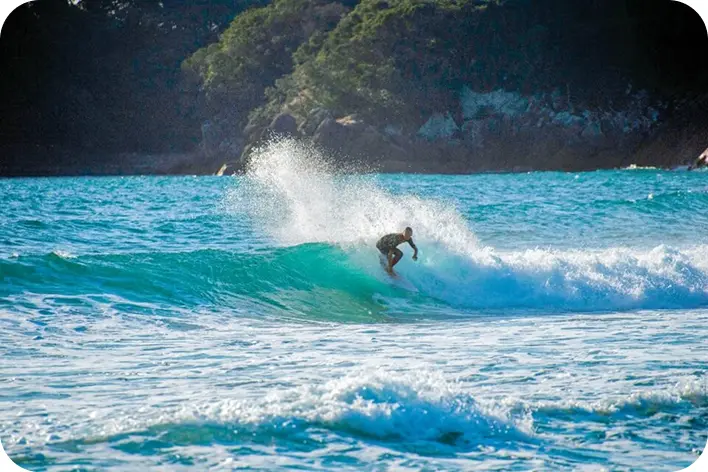 高知県の美しい海で波に乗るサーファーと砕ける白いしぶき
