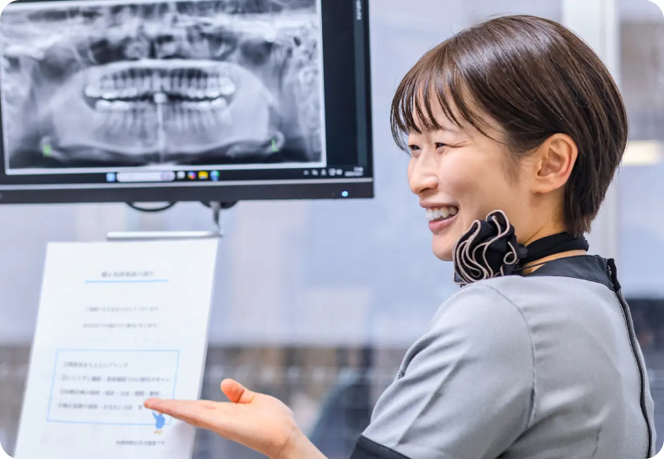 パノラマレントゲン画像の前で説明を行う歯科医院スタッフ