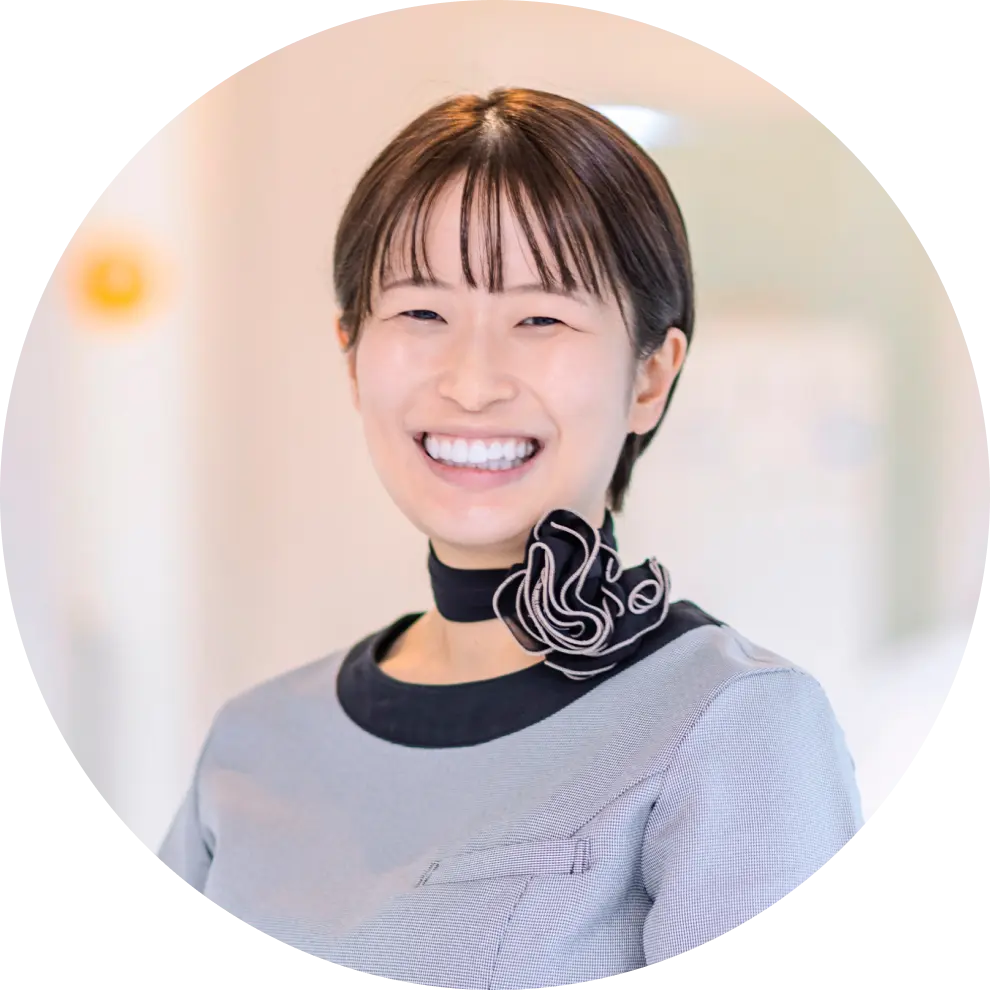 グレーの制服に黒いリボンをつけた女性スタッフの笑顔写真